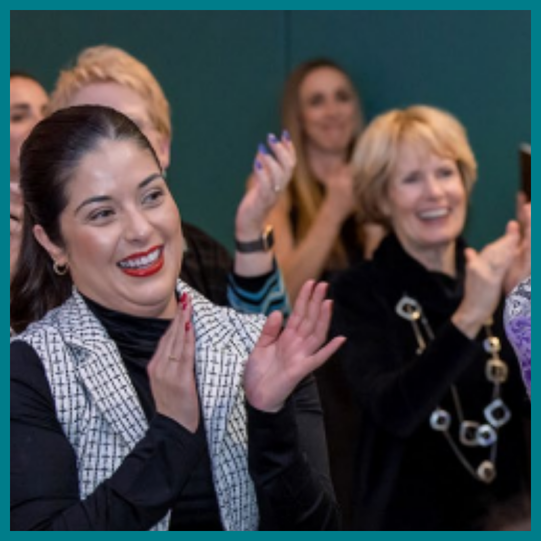 A group of women clapping and smiling toward a speaker