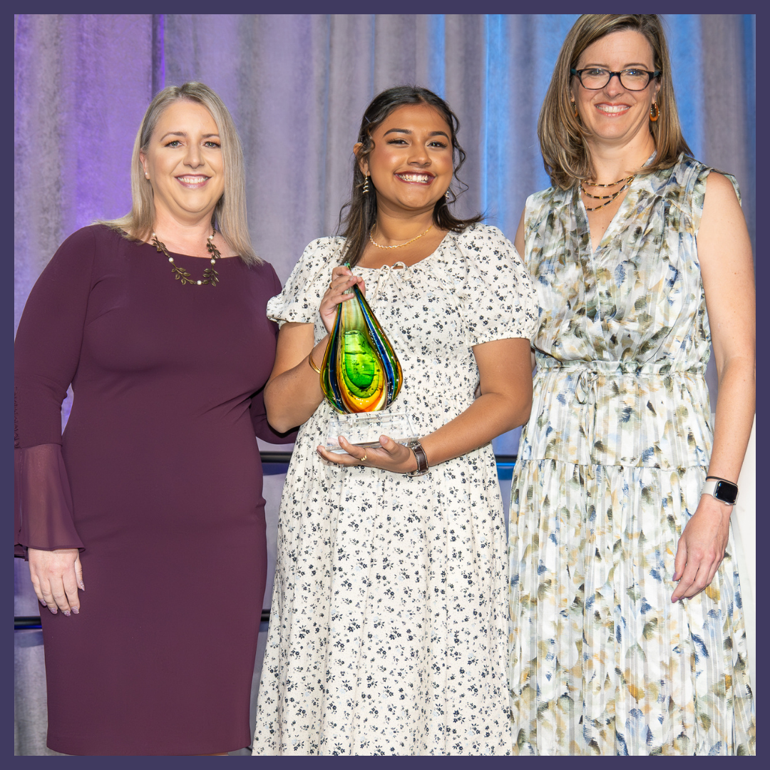 2024 Dottie Lamm Award winner, Gitanjali Rao, smiles with her award onstage at 2024 Annual Luncheon